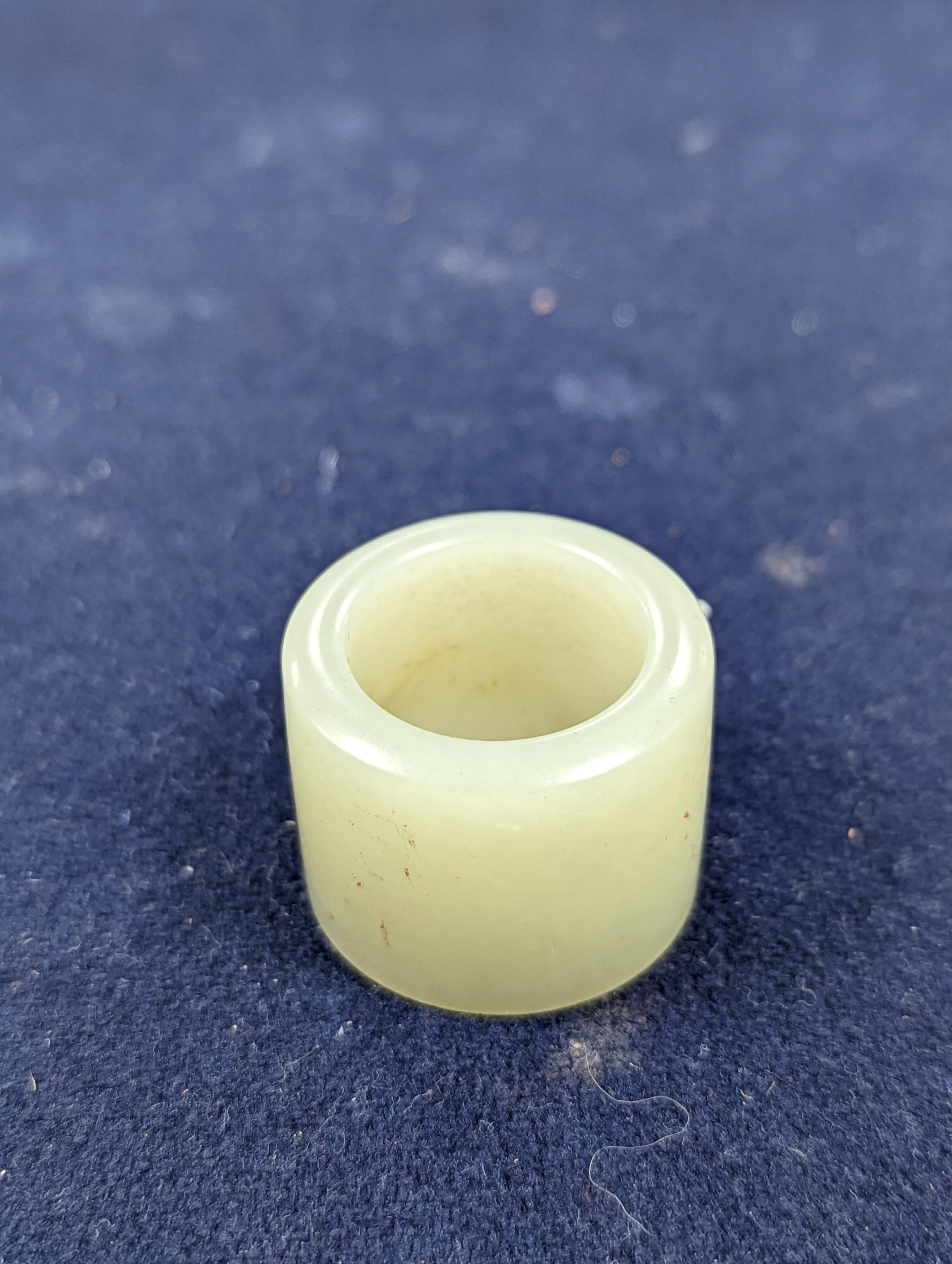 A 19th century Chinese pale celadon jade archer’s thumb ring, inscribed, 3 cm diameter